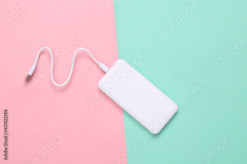 External portable battery (power bank) on blue-pink pastel background. Top view. Flat lay