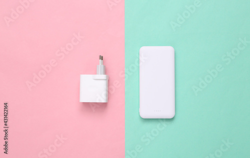 External portable battery (power bank) with charging device on a blue pink background. Top view. Flat lay
