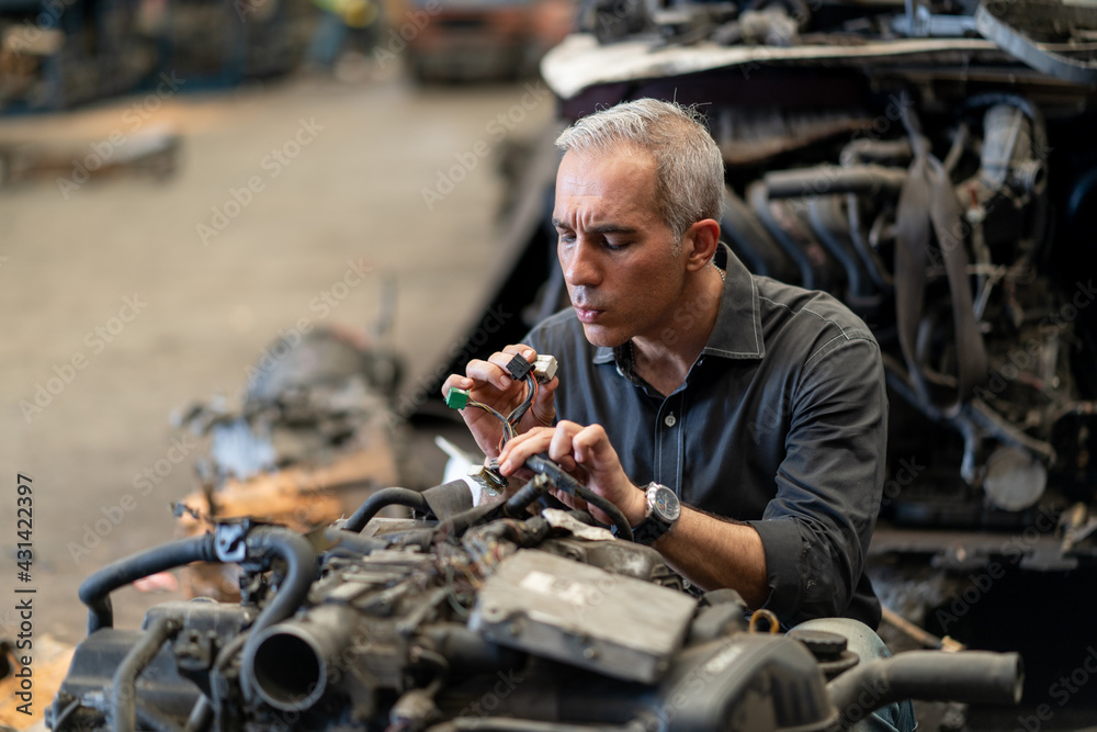 senior engineer checking old used car engine in machinery parts shop warehouse. old technician man Repair vehicle automobile machine in Recycle motor factory