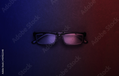 Classic eyeglasses in neon light. Top view.