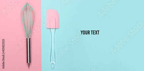 Kitchen spatula and whisk on pink blue pastel background. Minimalism. Copy space. Top view