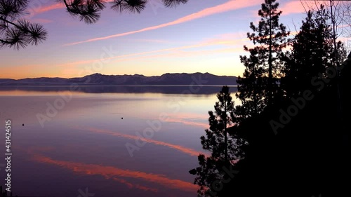 Amazing orange jet contrails are reflected on the placid lake surface of Lake Tahoe, California, Nevada. photo