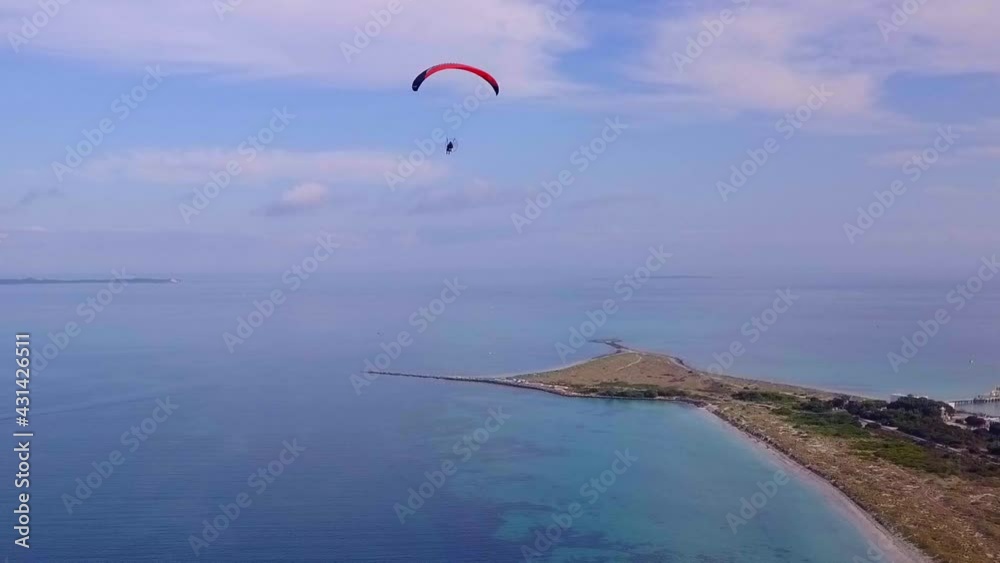 High aerial view of ocean headland towards horizon with paraglider ascending out of shot High aerial view of ocean headland towards horizon with paraglider ascending out of shot