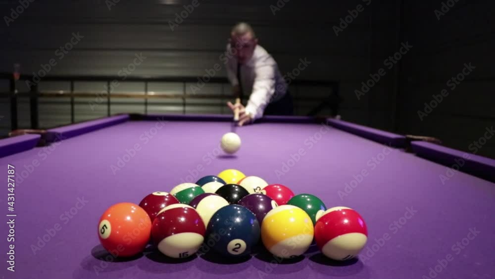 A guy breaking a pool table to start the game.