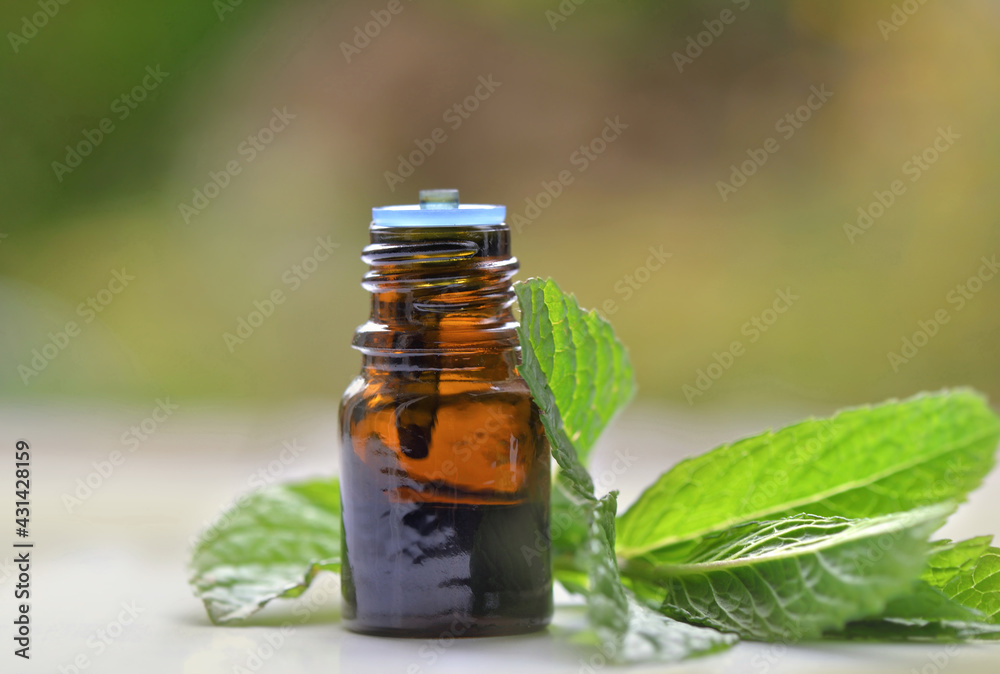 mint leaf with a bottle of aromatic oil on blur background mint leaf with a bottle of aromatic oil on blur background