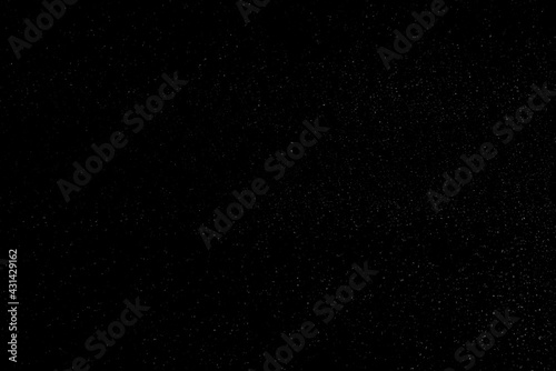 Chaotic white bokeh on a black background. light spots texture. abstraction. falling snow. starry sky. bright glare of light texture
