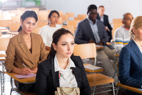 Portrait of female attentively listening to motivation lecture with colleagues at conference