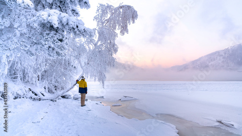 A guy in a snowy winter forest on the bank of a frozen river trees in white and his bright yellow clothes. The Fabulous Forest of Narnia