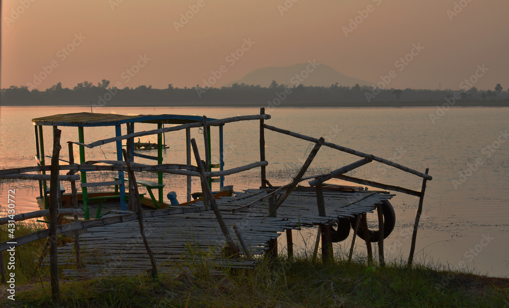 a broken bridge leading to the lake and a boat captured during sunset.
