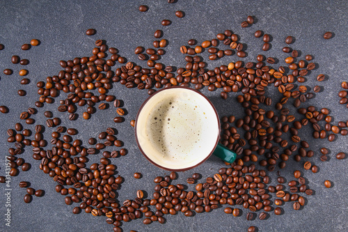 Cup of coffee on a gray table with coffee beans and coffee leaves. Top view.