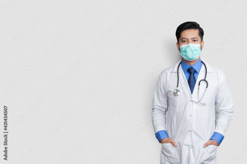 Young male doctor face covered with mask and hands in coat pocket over isolated background, health concept Young male doctor face covered with mask and hands in coat pocket over isolated background, health concept