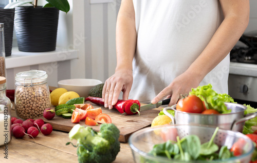 Healthy lifestyle and wholesome food concept. Pregnant women in early pregnancy preparing a healthy breakfast or dinner from fresh vegetables in the home kitchen