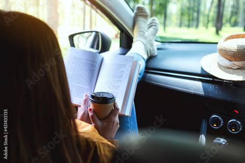 A woman reading book and drinking coffee in the car photo