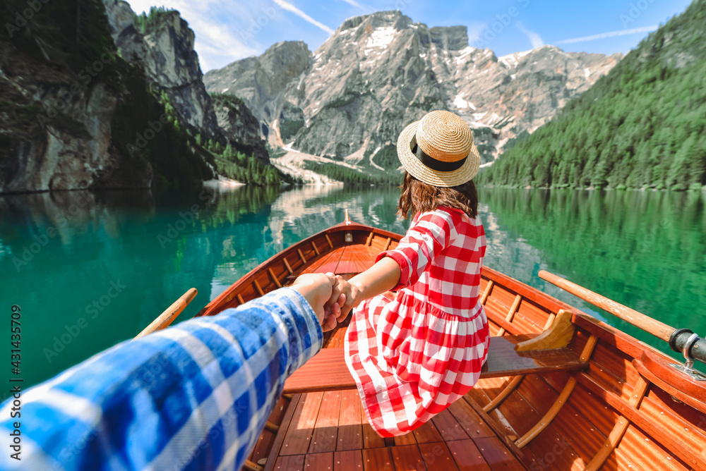 follow me concept. couple holding hands at wooden boat at mountain lake