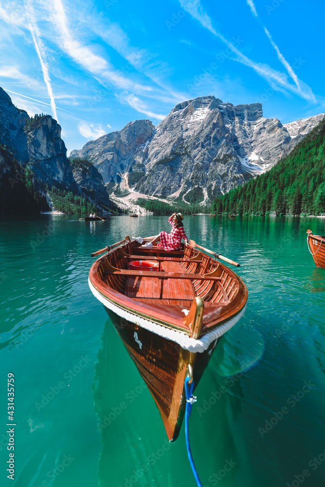 woman sitting in big brown boat at lago di braies lake in Italy