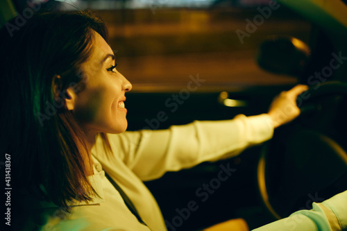 Close-up of happy woman enjoying while driving car at night.