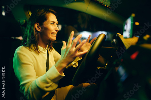 Young woman feeling stressed due to traffic while driving car at night.