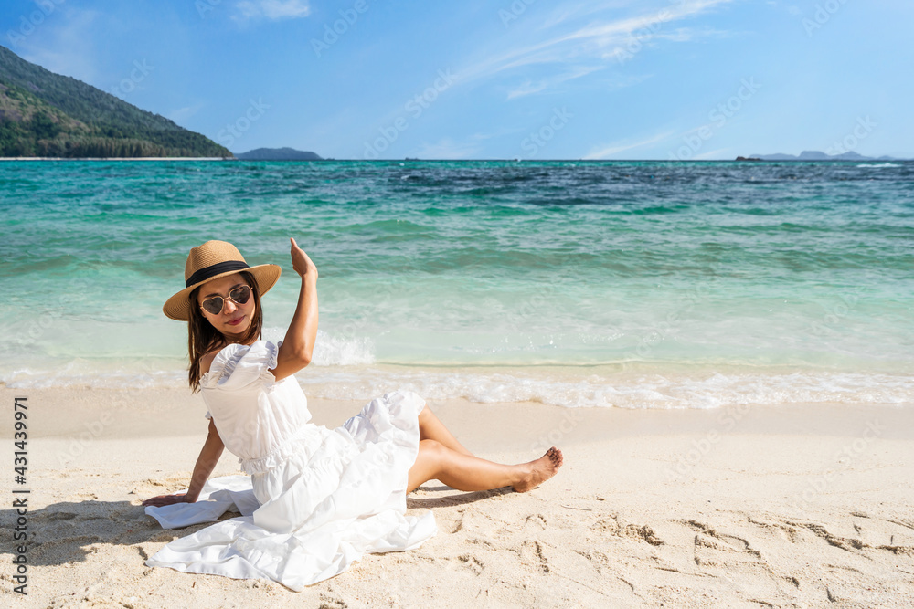 Young woman traveler wearing sunglasses covering face by hand to protect UV rays from the sun at tropical sandy beach on sunny day, Skin care and eyes protect concept Young woman traveler wearing sunglasses covering face by hand to protect UV rays from the sun at tropical sandy beach on sunny day, Skin care and eyes protect concept