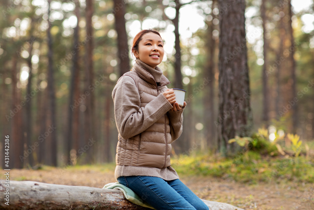 picking season, leisure and people concept - young asian woman with mug drinking tea in autumn forest picking season, leisure and people concept - young asian woman with mug drinking tea in autumn forest