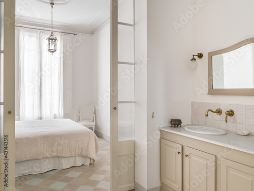 Fototapeta Naklejka Na Ścianę i Meble -  Bright bathroom interior with view to bedroom. Cozy bed with beige linen. Retro and vintage style.