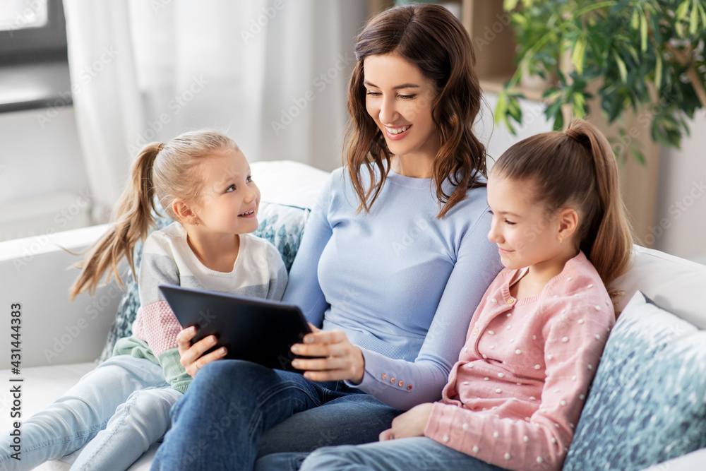 people, family and technology concept - happy mother and two daughters with tablet pc computer at home