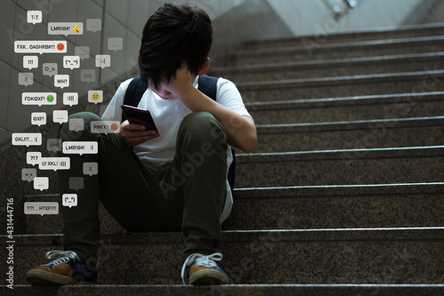Cyberbullying - social media harassment concept. Young asian preteen, teenager boy looking at his smartphone feeling frustrated after reading bad comments. Text emoticons. Bully, Teen mental health