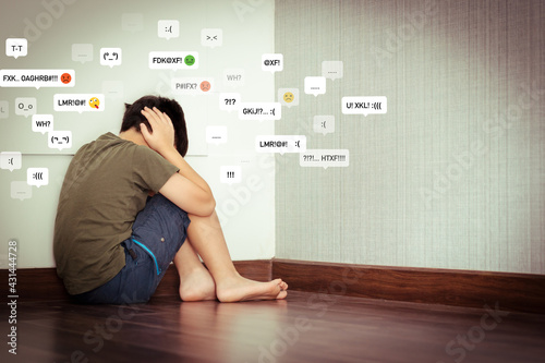 Young Asian preteen/teenage boy sitting alone at the corner of room, covering his ears, face down crying. Cyber Bullying, Teen problems, Loneliness, Traumatic, Stressed, frustrated and lost.