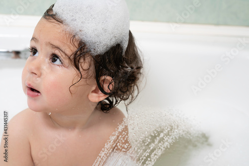 1 year old girl, bathing in the bathroom, foam on her head