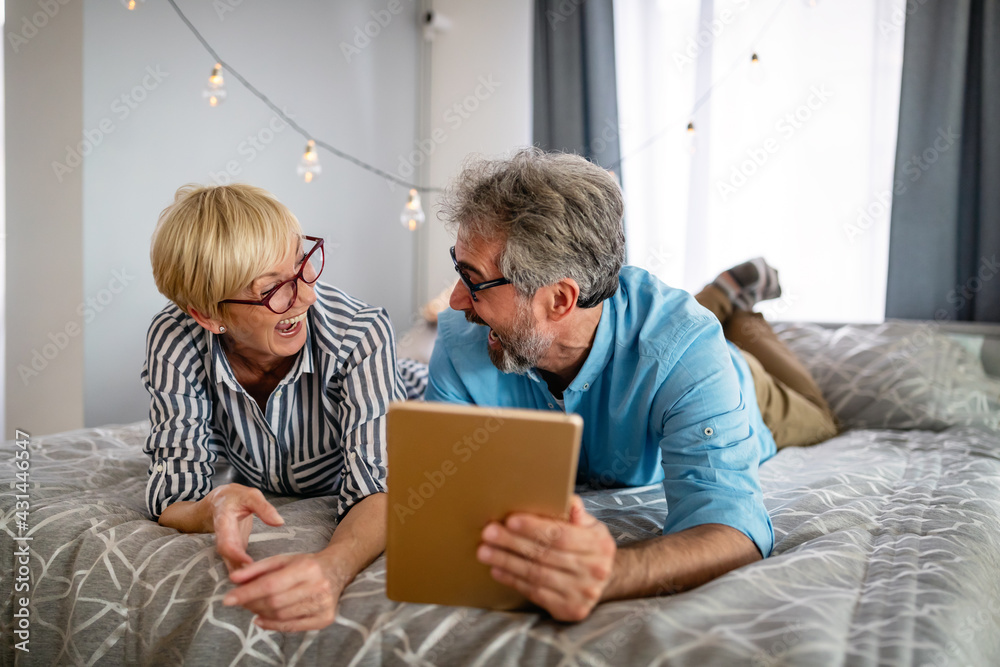 Happy smiling mature couple using digital tablet at home Happy smiling mature couple using digital tablet at home
