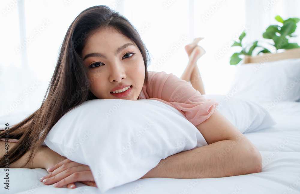 Beautiful young naughty sexy girl with long hair lying down on pillow on white bed end in bright morning and seductively glancing with smile to special one of happy romantic day Beautiful young naughty sexy girl with long hair lying down on pillow on white bed end in bright morning and seductively glancing with smile to special one of happy romantic day