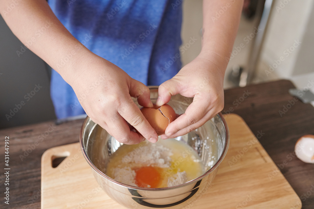 Female hands crack egg into bowl for making dough 