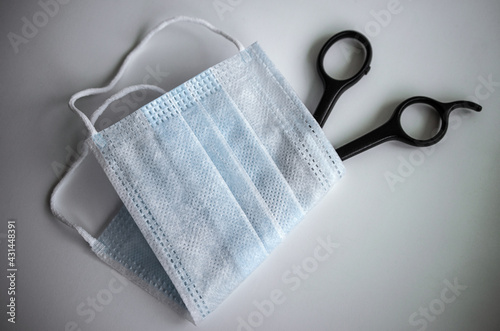 Hairdressing scissors wrapped in a medical mask, restrictions of hairdressing salons during the coronovirus pandemic.