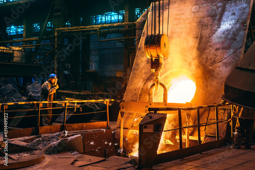 Fotografia Molten iron pouring from blast furnace into ladle container, steel foundry factory, heavy metallurgy industry