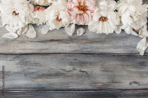 Fototapeta Naklejka Na Ścianę i Meble -  Decorative floral frame, banner made of pink and white peonies flowers. Old grey wooden table background. Empty copy space. Flat lay, top view. Picture for blog, summer wedding or birthday.