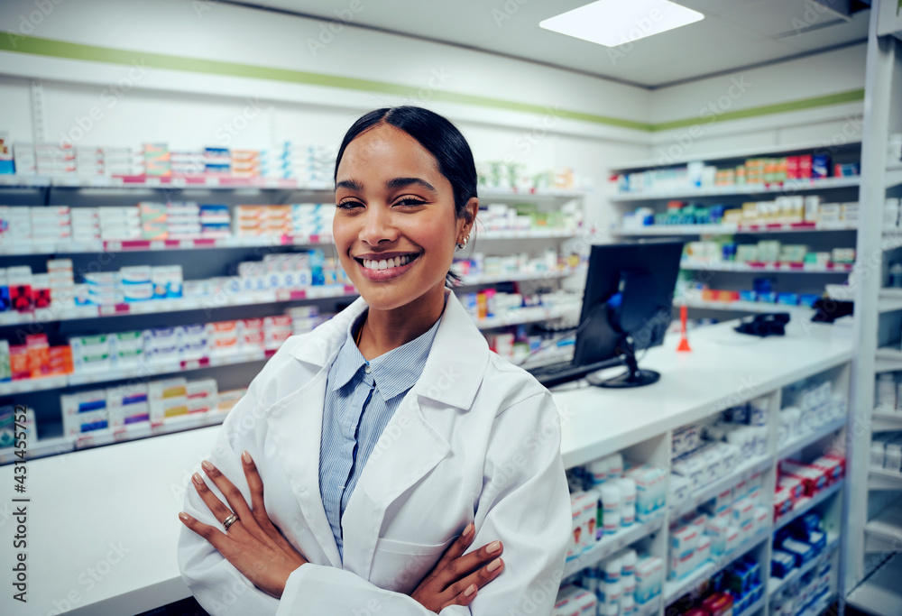 Cheerful young woman in labcoat standing with folded hands in chemist