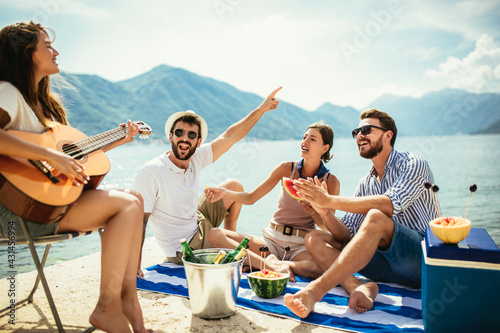 Happy friends partying on the beach with drinks