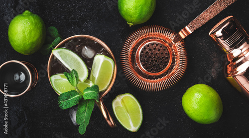 Moscow Mule. Preparation cocktail with ginger beer, vodka, lime and ice. Copper bar tools. Black bar counter. Top view