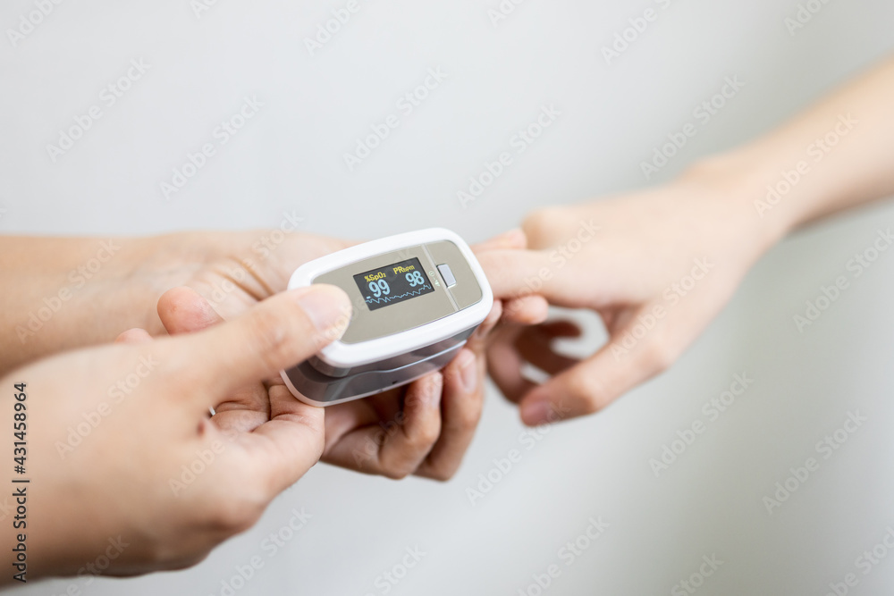 Hand of child girl with fingertip pulse oximeter on finger for examination of the lung disease,checking for Coronavirus COVID-19 infection from oxygen saturation at home,measuring heart rate (pulse). Hand of child girl with fingertip pulse oximeter on finger for examination of the lung disease,checking for Coronavirus COVID-19 infection from oxygen saturation at home,measuring heart rate (pulse).