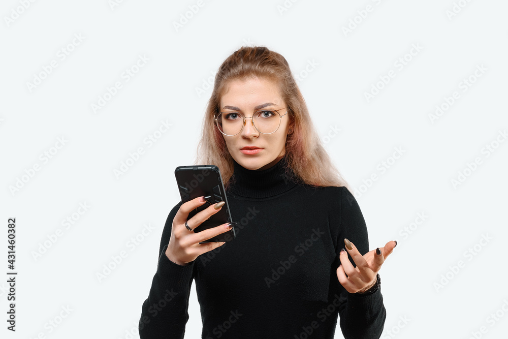 Image of a confused young beautiful woman in casual clothes holding her smart phone. White background Image of a confused young beautiful woman in casual clothes holding her smart phone. White background