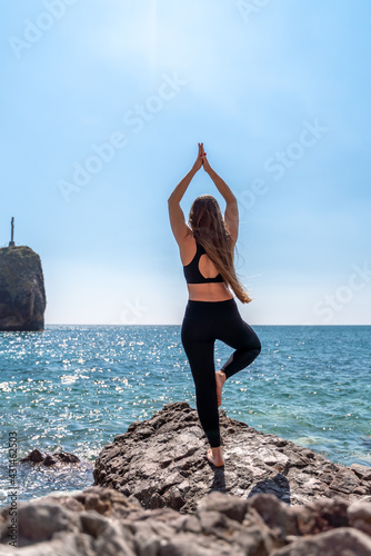 Young beautiful sportwoman practicing yoga. Coach teaching tree pose at the beach