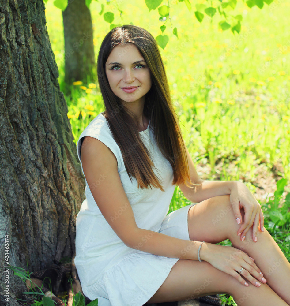 Portrait of beautiful young woman sitting on a grass in summer park Portrait of beautiful young woman sitting on a grass in summer park