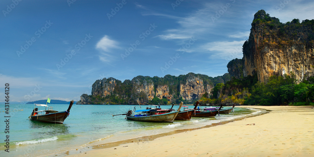long tail boat, in white sand beach in  andaman sea with view of limestone island 