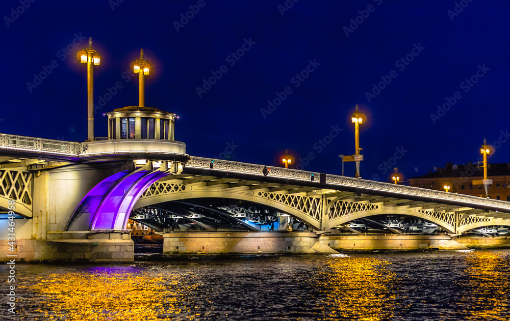 A bridge spanning the Neva river, illuminated by lanterns and floodlights on a white night in Saint Petersburg