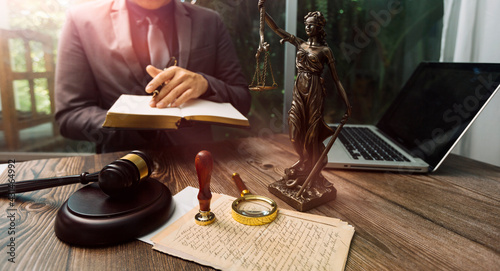 Justice and law concept.Male judge in a courtroom with the gavel, working with, computer and docking keyboard, eyeglasses, on table in morning light