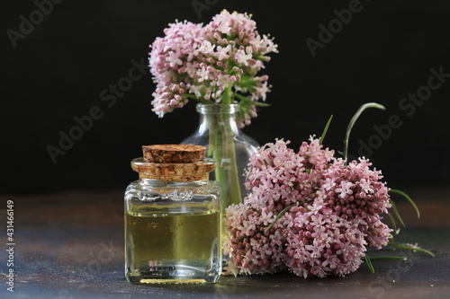 Essential oil in bottle with blooming valerian plant