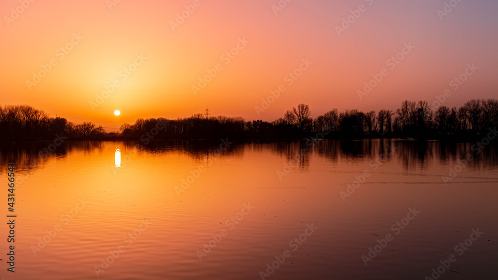 Beautiful sunset with reflections on a day with lots of sahara dust in the air near Plattling, Isar, Bavaria, Germany