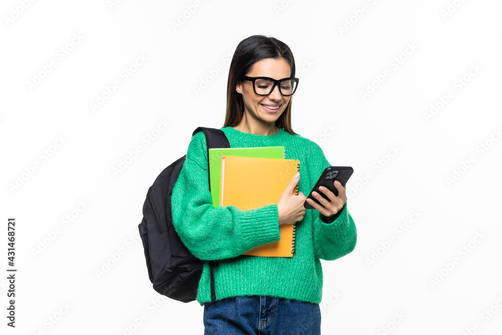 Young woman university student with backpack and books sending a sms on cell phone, isolated on white background Young woman university student with backpack and books sending a sms on cell phone, isolated on white background