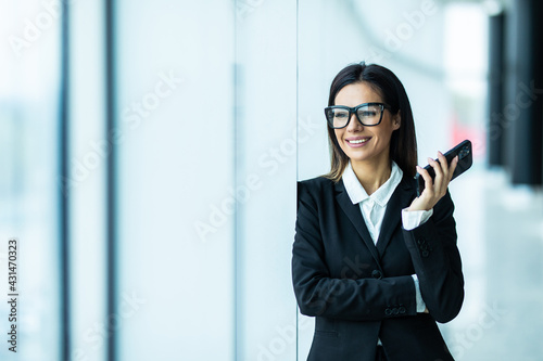Businesswoman Making Phone Call Standing By Office Window
