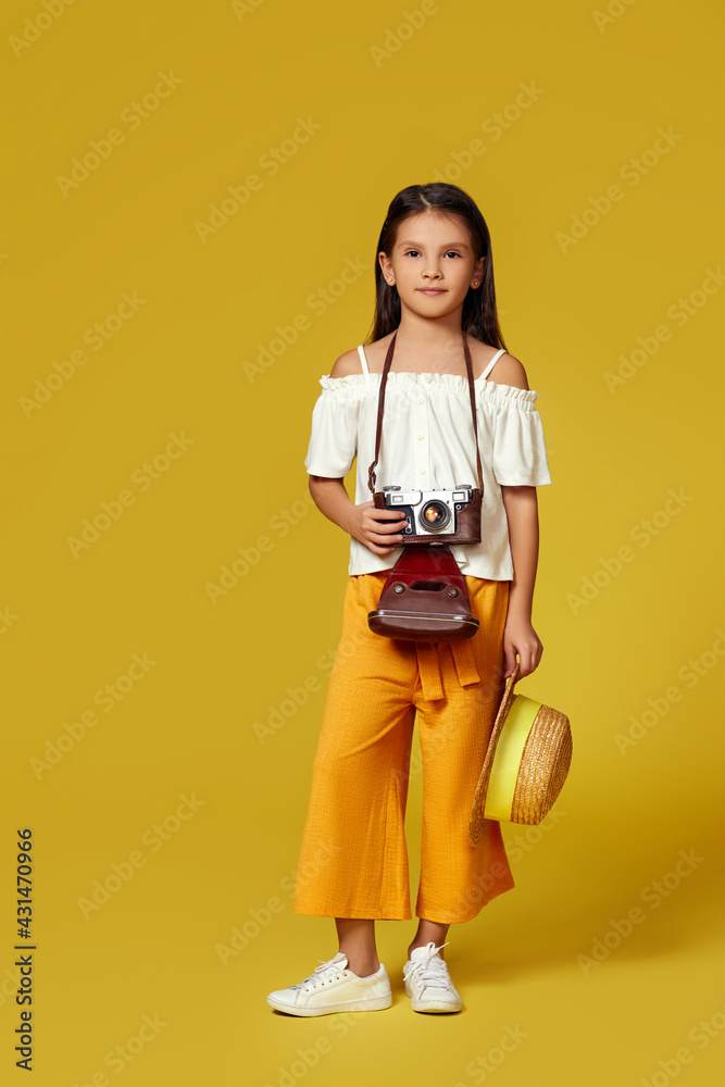 Fototapeta premium cute little girl with retro camera on yellow background.