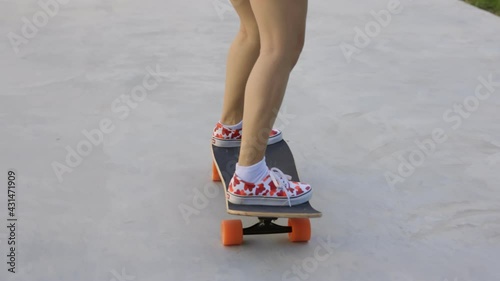 Attractive Asian woman with safety skateboarding knee pad skating at skateboard park .Female enjoy summer outdoor active lifestyle play extreme sport surf skate at public park.